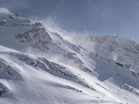 a mountain covered in snow with a skiier coming down the side of it to go through