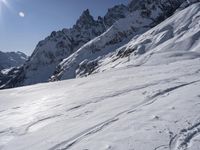 the person is skiing down the snow covered mountain slope and is in the sun looking forward