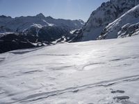 the person is skiing down the snow covered mountain slope and is in the sun looking forward