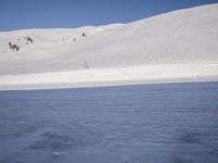 a person skiing in the snow by a mountain shoreline in the winter season,