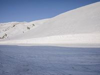 a person skiing in the snow by a mountain shoreline in the winter season,