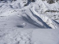 a man riding skis across a snow covered slope covered in snow next to mountains