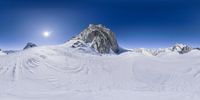 two people snowboarding on top of the mountain side under a clear sky, with many snow covered mountains in front