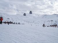 many people on skis and snowboards on the slopes near a gondola lift