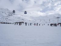 many people on skis and snowboards on the slopes near a gondola lift