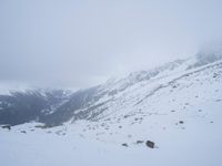 a skier skiing up a mountain with many snowcapped mountains in the background in winter