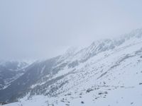 a skier skiing up a mountain with many snowcapped mountains in the background in winter