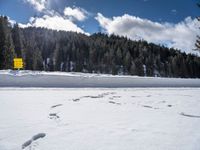 a person wearing skis on a snow covered field in the woods above mountains with a sign that reads beware of all others