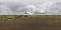 a panoramic view of the prairie under a cloudy sky and in front of green hills