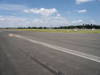 the empty runway of an airplane runway, with only a single car parked on it