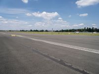 the empty runway of an airplane runway, with only a single car parked on it