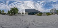 a fisheye view of the entrance to an office building with a sky background and several clouds