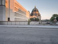 an empty street next to two tall buildings with domes in the background is an older building