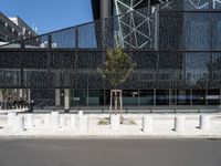 a building made of glass next to a road and some trees on either side of it