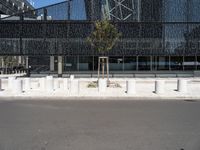 a building made of glass next to a road and some trees on either side of it