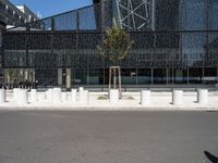 a building made of glass next to a road and some trees on either side of it