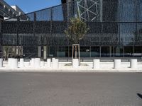 a building made of glass next to a road and some trees on either side of it