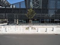 a building made of glass next to a road and some trees on either side of it