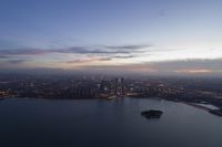 a wide open cityscape and a large body of water at dusk with a very small island below