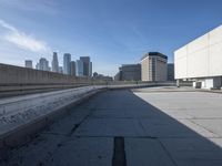 a concrete wall and a street next to some buildings with buildings in the background behind it