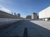 a concrete wall and a street next to some buildings with buildings in the background behind it