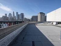 a concrete wall and a street next to some buildings with buildings in the background behind it