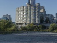 the skyscraper building with a huge amount of windows in it is standing alone and surrounded by trees