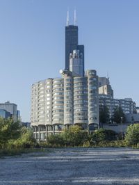 the skyscraper building with a huge amount of windows in it is standing alone and surrounded by trees
