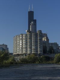 the skyscraper building with a huge amount of windows in it is standing alone and surrounded by trees