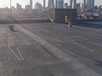 an empty parking lot that contains several lines and blocks in the city skyline in a shadow