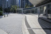 a person sitting at the bench in front of a mall that is empty of people