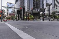 an empty street lined with tall building and red traffic lights and green traffic signal towers
