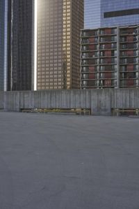 a group of skyscrapers near a bench in the city park with a skate board