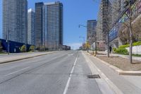 a deserted street surrounded by tall buildings on the other side of it with a stop sign