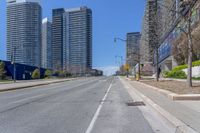 a deserted street surrounded by tall buildings on the other side of it with a stop sign