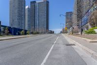 a deserted street surrounded by tall buildings on the other side of it with a stop sign