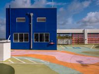 the empty court in front of a school with colorful markings on it has a fire hydrant on top