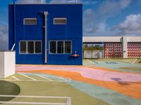 the empty court in front of a school with colorful markings on it has a fire hydrant on top