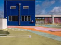 the empty court in front of a school with colorful markings on it has a fire hydrant on top
