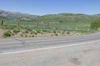 there is a mountain with wildflowers and green hills behind it and a sign that is pointing towards the left corner