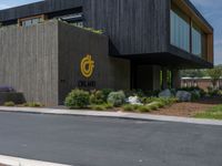 a building with a logo painted on the side near a street that has a sidewalk next to it