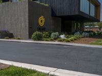 a building with a logo painted on the side near a street that has a sidewalk next to it