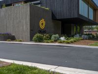 a building with a logo painted on the side near a street that has a sidewalk next to it