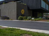 a building with a logo painted on the side near a street that has a sidewalk next to it