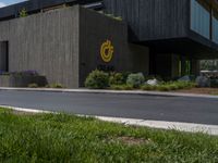 a building with a logo painted on the side near a street that has a sidewalk next to it