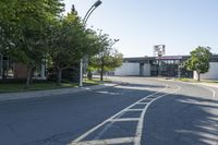 the intersection of a street in front of a building with lots of trees and shrubs