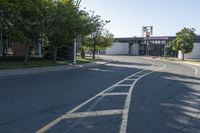 the intersection of a street in front of a building with lots of trees and shrubs