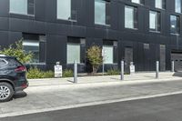 two cars parked near a parking lot near a black building with a sign indicating parking meters