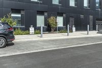 two cars parked near a parking lot near a black building with a sign indicating parking meters