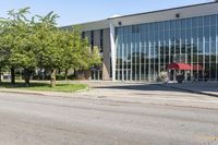 a large, open building with large windows on the ground and street near it with trees